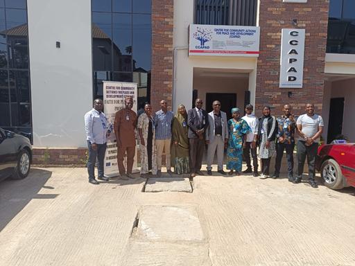 CCAPAD volunteer smiling while holding a Peace Begins with a Smile poster